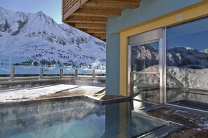 Un edificio moderno con piscina de cristal que refleja montañas nevadas.