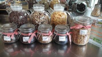 A variety of glass jars with labels, some tied with red and white checkered ribbons, containing different food items like nuts and dried fruits.