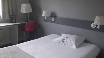 Una habitación de hotel con una cama, un escritorio, una silla y un aire acondicionado de pared.