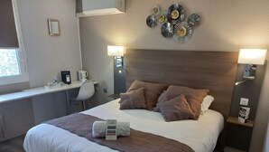 A hotel room with a bed, bedside tables, a desk, and a chair.