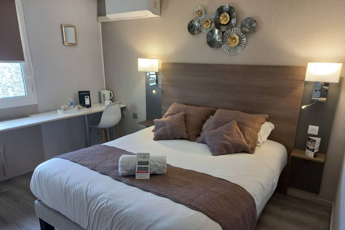 Ein Hotelzimmer mit einem Bett, Nachttischen, einem Schreibtisch und einem Sessel.