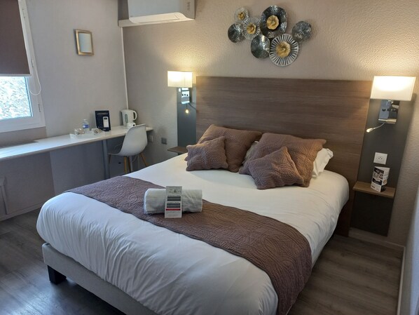 Una habitación de hotel con una cama, mesitas de noche, un escritorio y una silla.