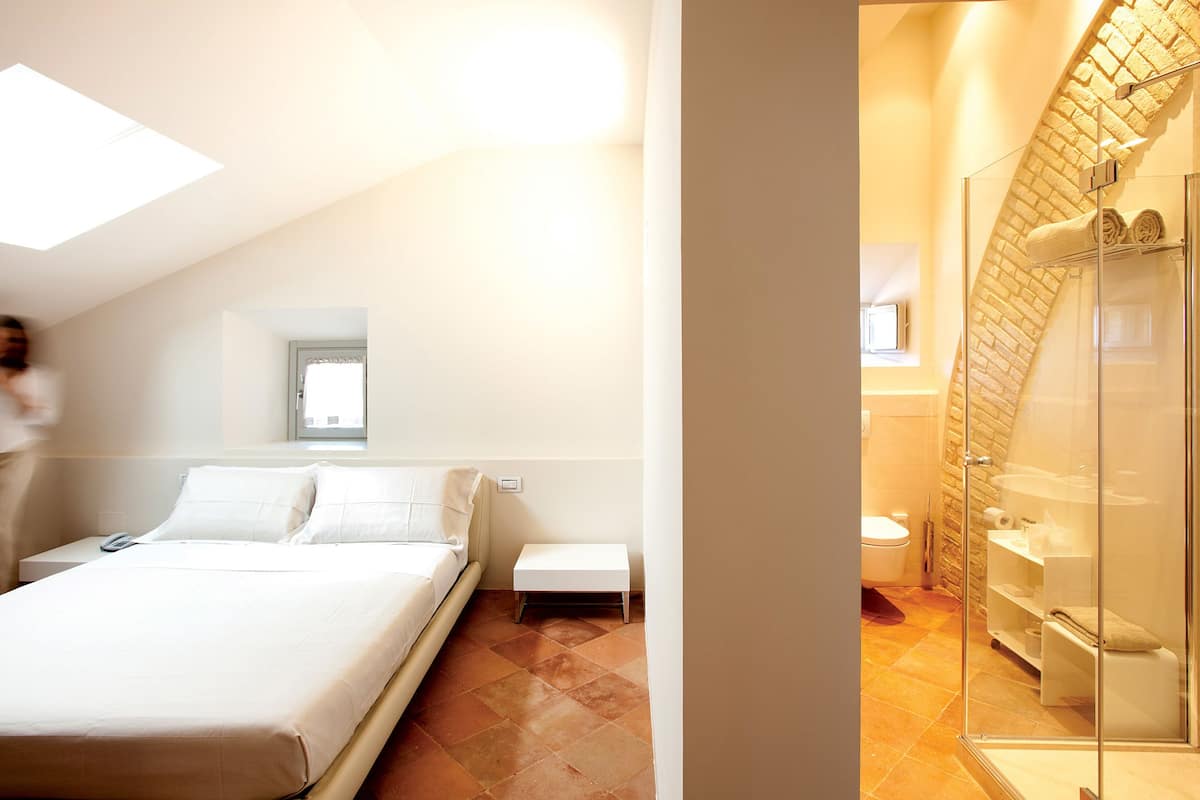 A bedroom with a bed, bedside table, and a small window.