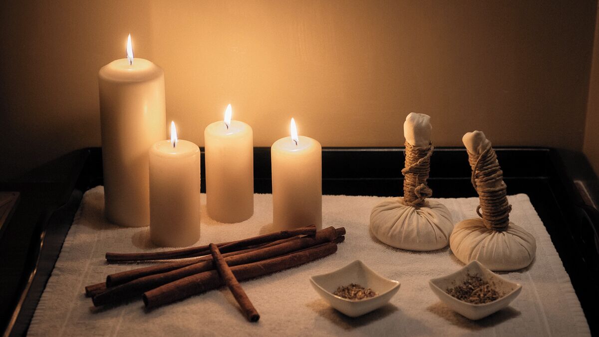 A set of candles, cinnamon sticks, and small bowls on a tray.