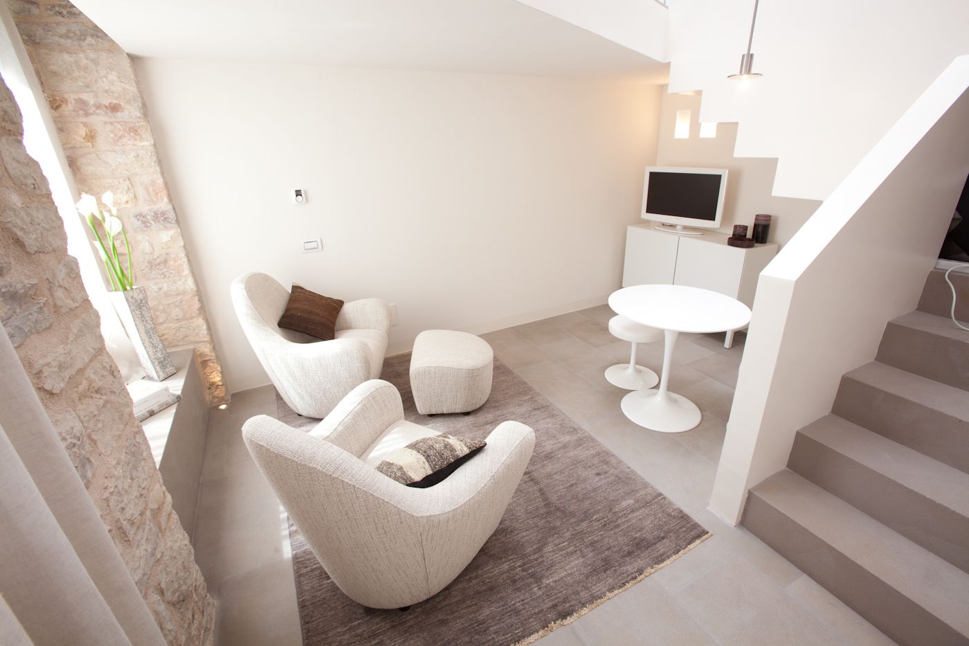 Una sala de estar moderna con un conjunto de sofá, una mesa de centro y un televisor sobre un mueble blanco.