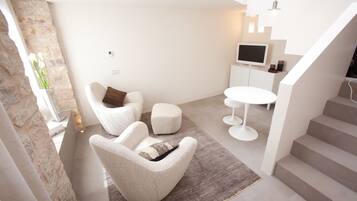 Una sala de estar moderna con un conjunto de sofá, una mesa de centro y un televisor sobre un mueble blanco.