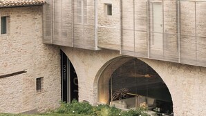 Un bâtiment en pierre doté d’arcades et d’un espace extérieur abrité aménagé en coin salon.