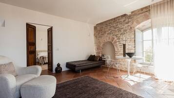 Una sala de estar moderna con una pared de piedra, un sofá, una mesa de comedor con sillas y un ventanal grande.