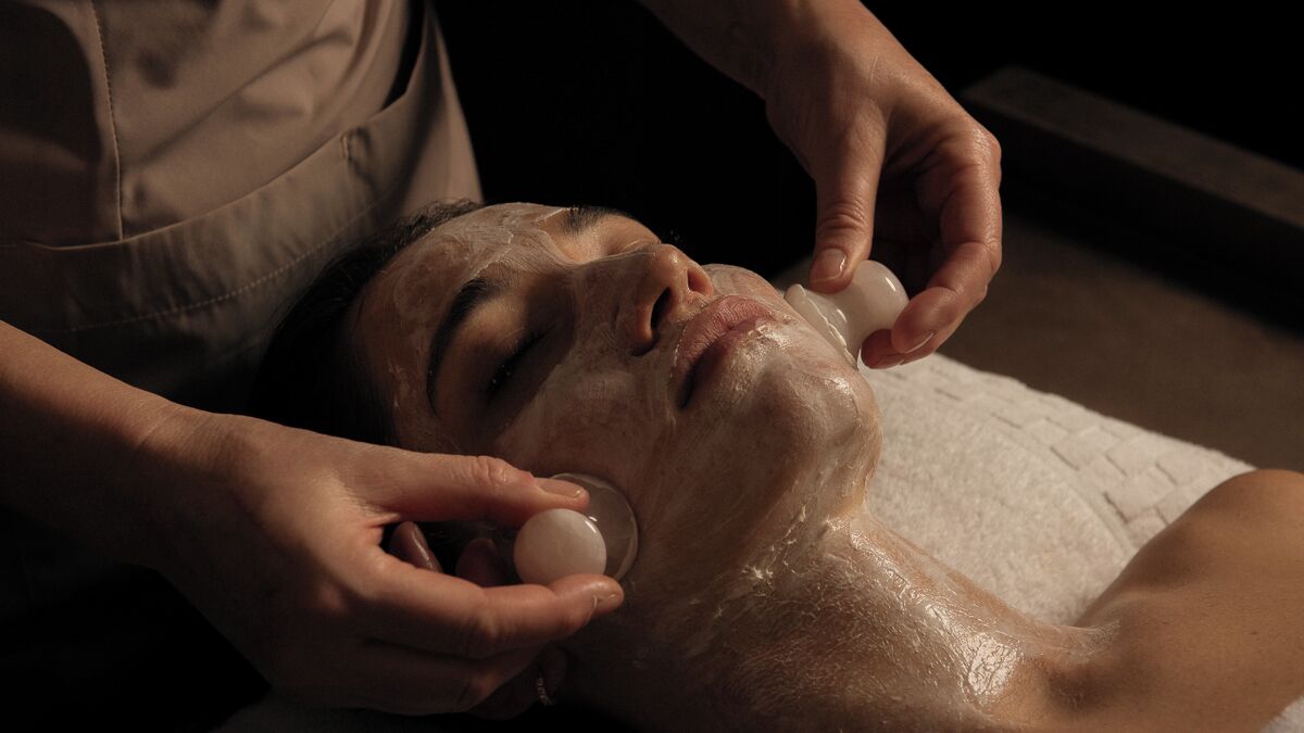 A person receiving a facial treatment with a towel and a white cloth.