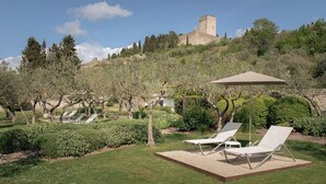 Un jardin agrémenté de chaises longues, d’une pergola et, en arrière-plan, d’un bâtiment historique.