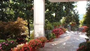 A covered patio area with potted plants and a tiled walkway. - Ostello di Bergamo (Bergamo)