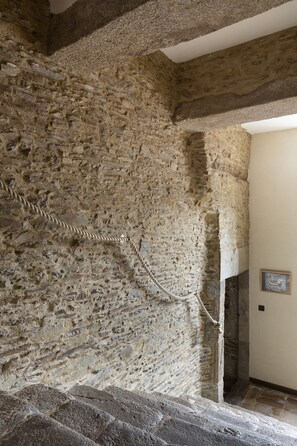 Un escalier en pierre menant à un niveau supérieur, avec une rambarde en corde.