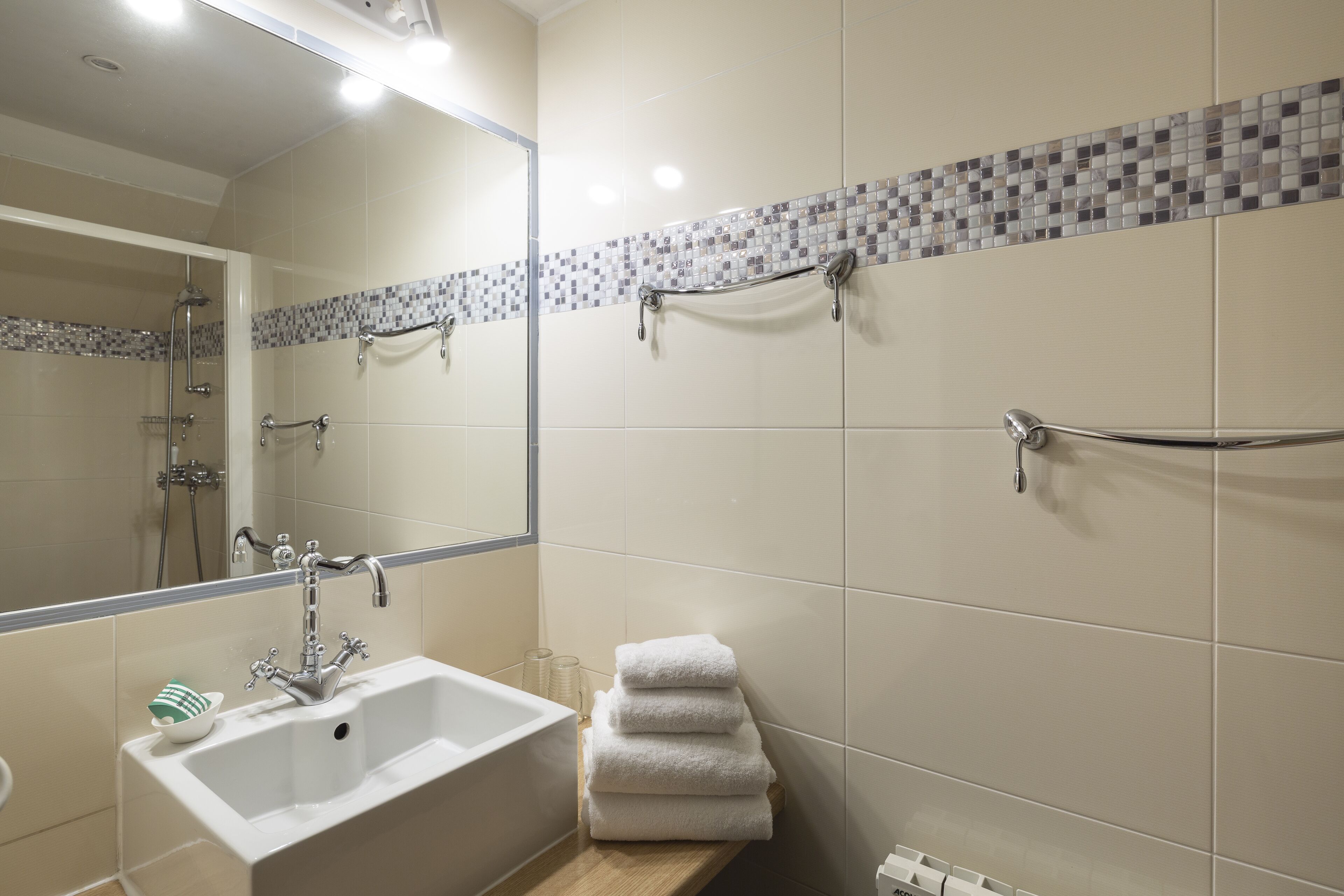 A bathroom with a sink, mirror, and shower.