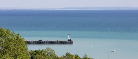 Eine Küstenansicht mit Leuchtturm, Steg und ruhiger See.