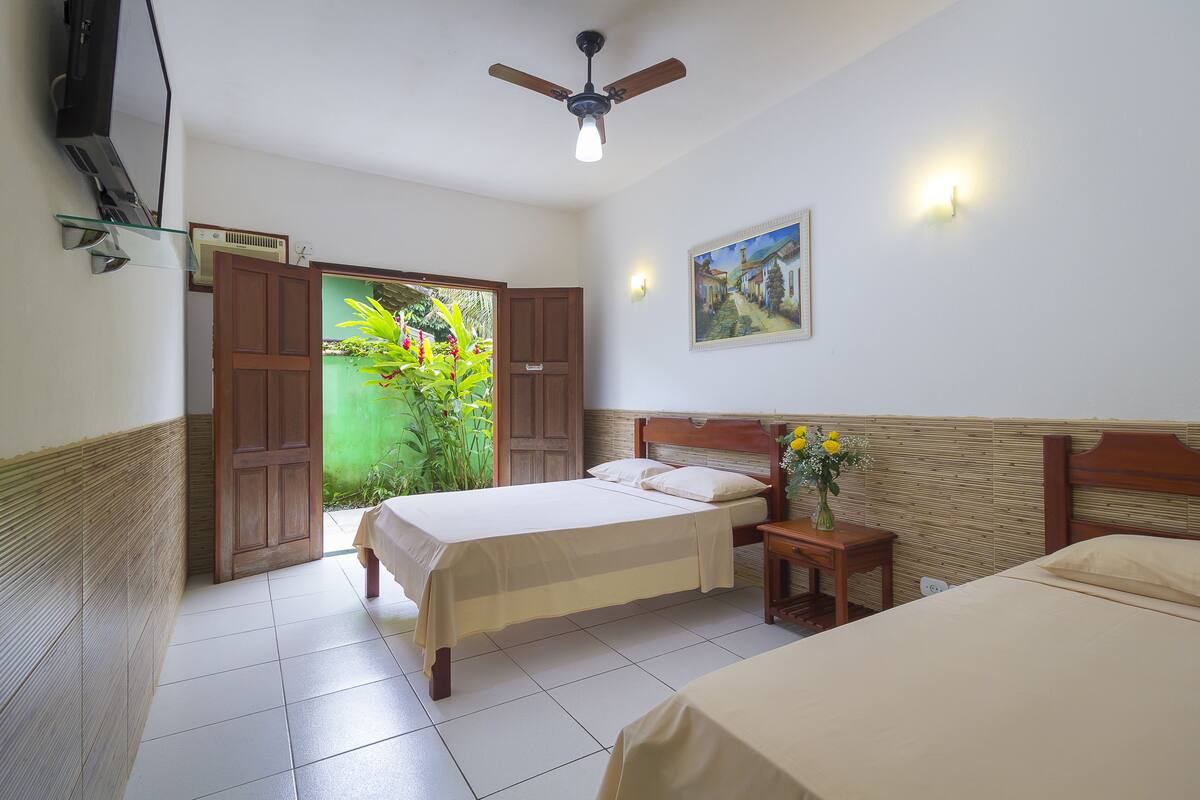 A hotel room with a bed, a nightstand, a ceiling fan, and a painting on the wall.