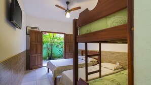 Une chambre avec des lits superposés, un ventilateur de plafond, une télévision et une porte donnant sur un jardin.