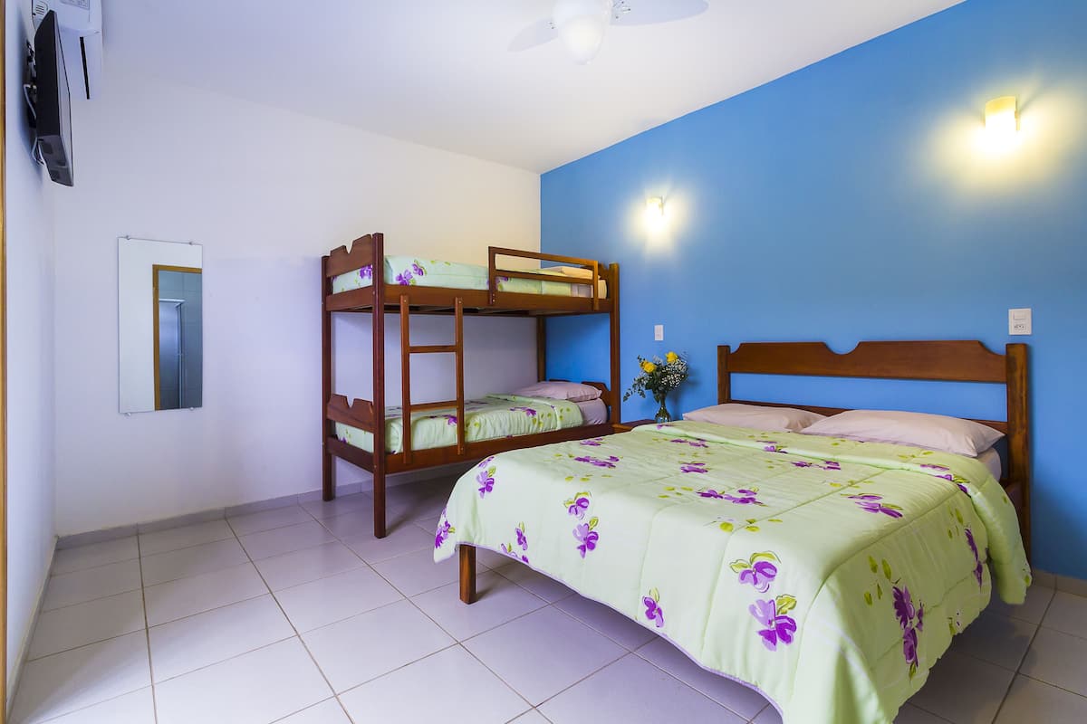 A room with bunk beds, a single bed, a mirror, and a ceiling fan.