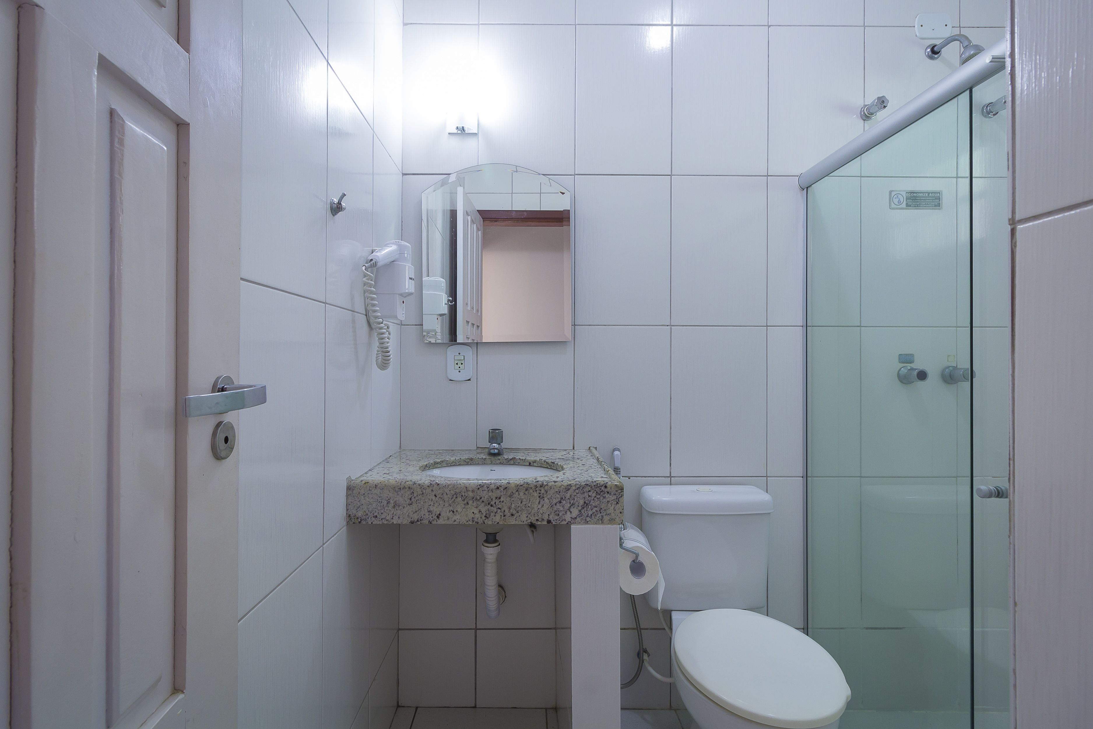 A bathroom with a marble sink, toilet, and a glass shower enclosure.