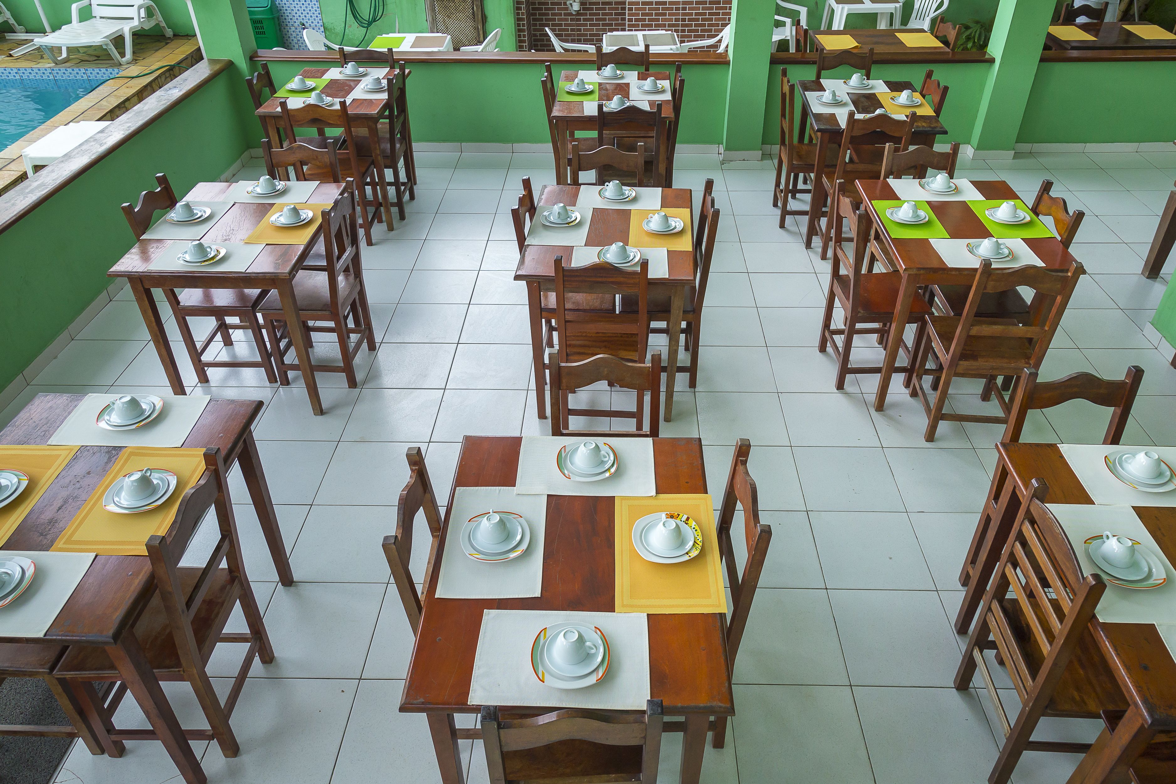 A dining area with multiple tables and chairs, each set with plates and bowls.