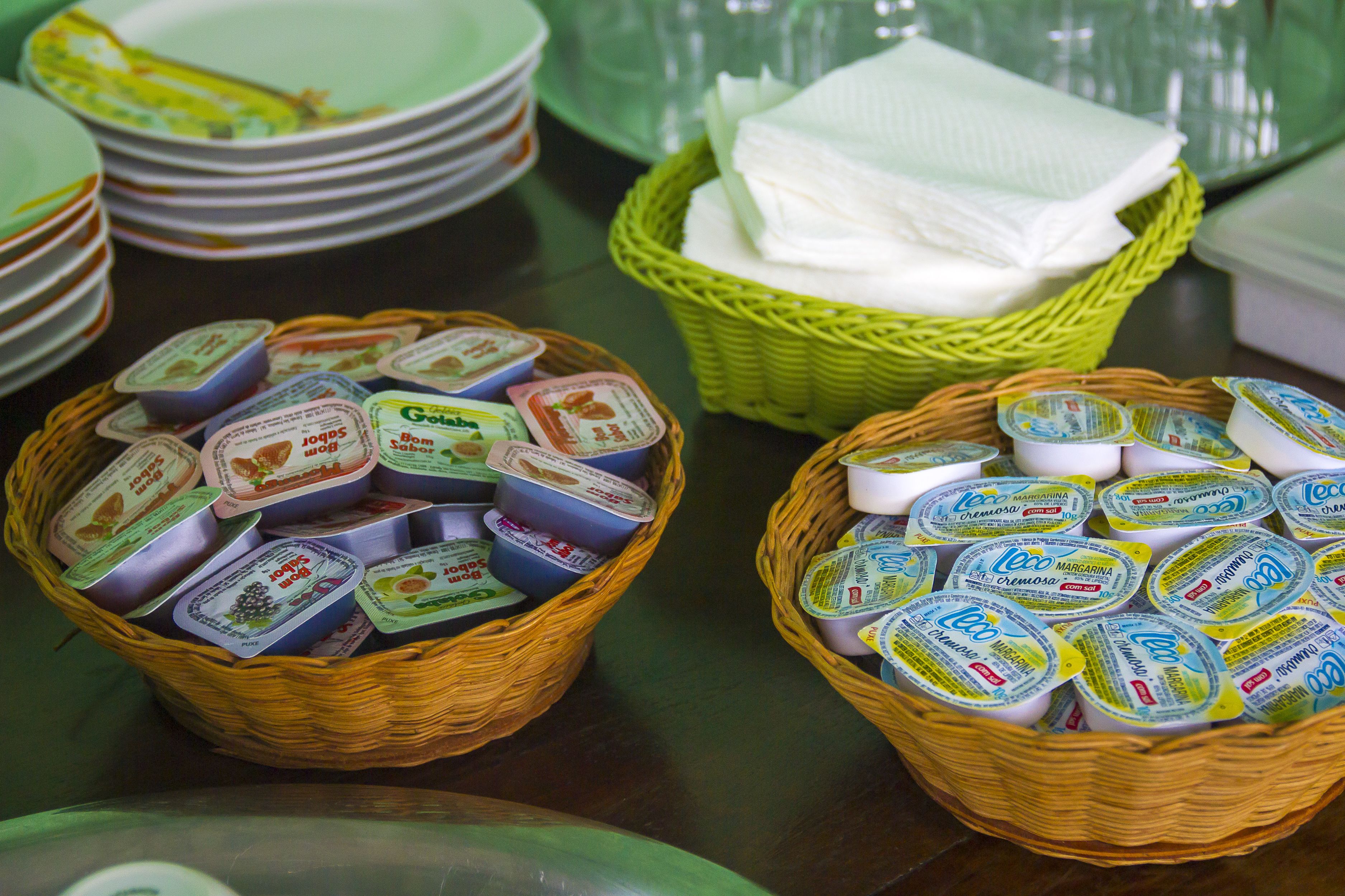 Two wicker baskets filled with yogurt containers, a stack of plates, and a green basket with napkins.