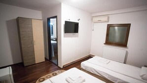 Una habitación de hotel con dos camas individuales, un armario, un televisor y una ventana con persianas.
