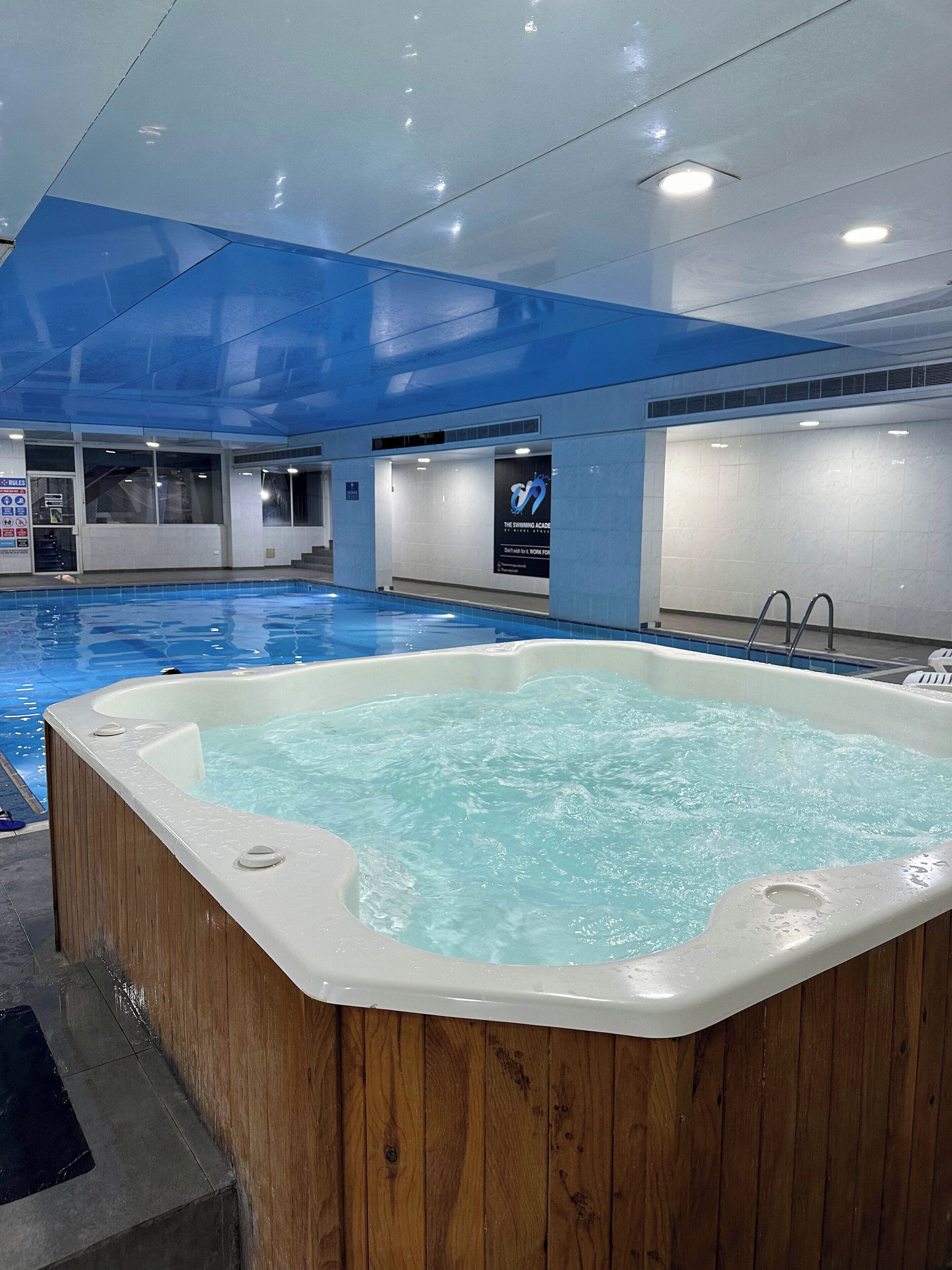 A swimming pool with a hot tub in the foreground.
