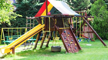 Ein Spielplatz mit Kletterwand, Rutschen und Schaukeln.