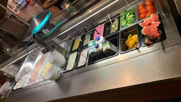 Een buffetgedeelte met diverse soorten eten, zoals fruit, groenten en zuivelproducten.