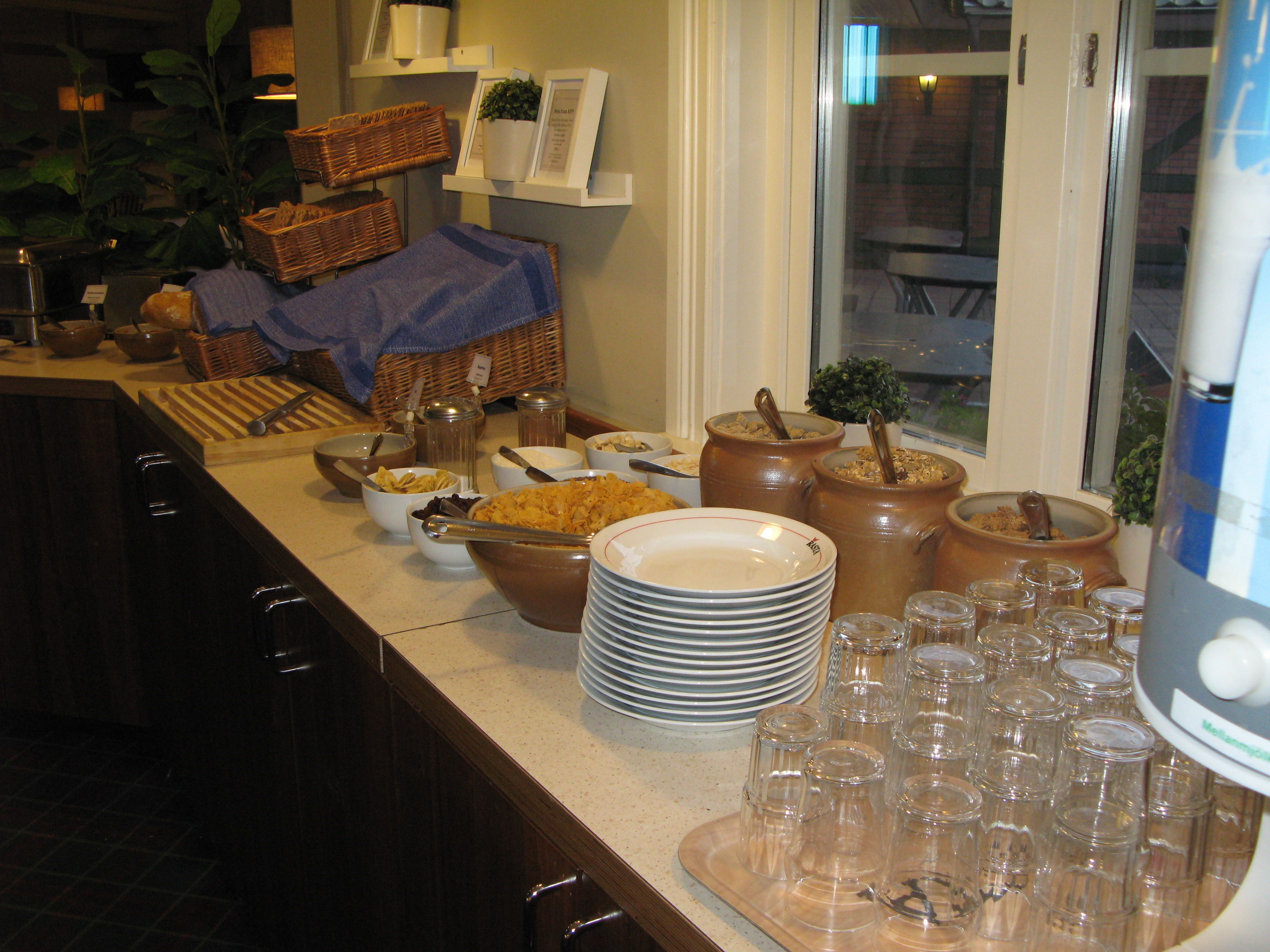 A buffet setup with various food items, serving utensils, and glassware.