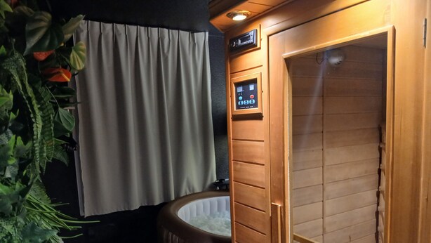 Un baño con bañera de madera, panel de control y zona de ducha.