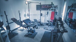 Un gimnasio con equipo de levantamiento de pesas, bancos y un cartel en la pared.