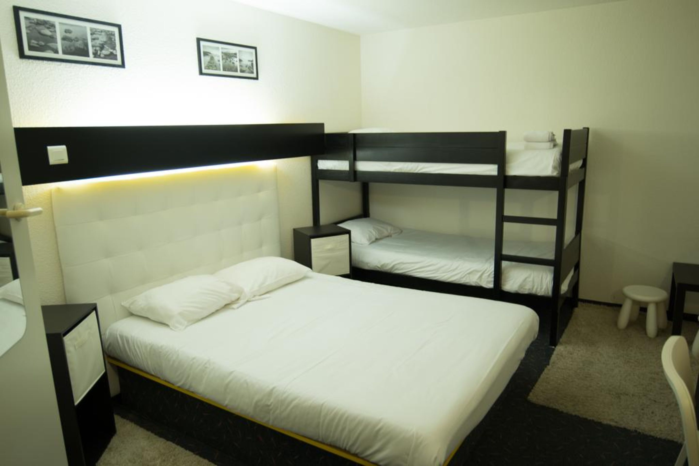 Camera con letto a castello, una testiera bianca, un comodino e un piccolo sgabello.