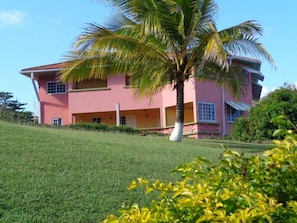 Stunning two-story building with a flat roof and second-floor balcony, set amidst a beautifully manicured lawn.
