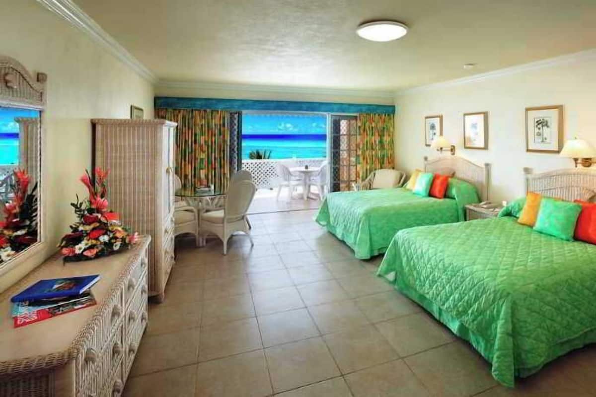 A hotel room with two beds, a desk, and a view of the ocean.