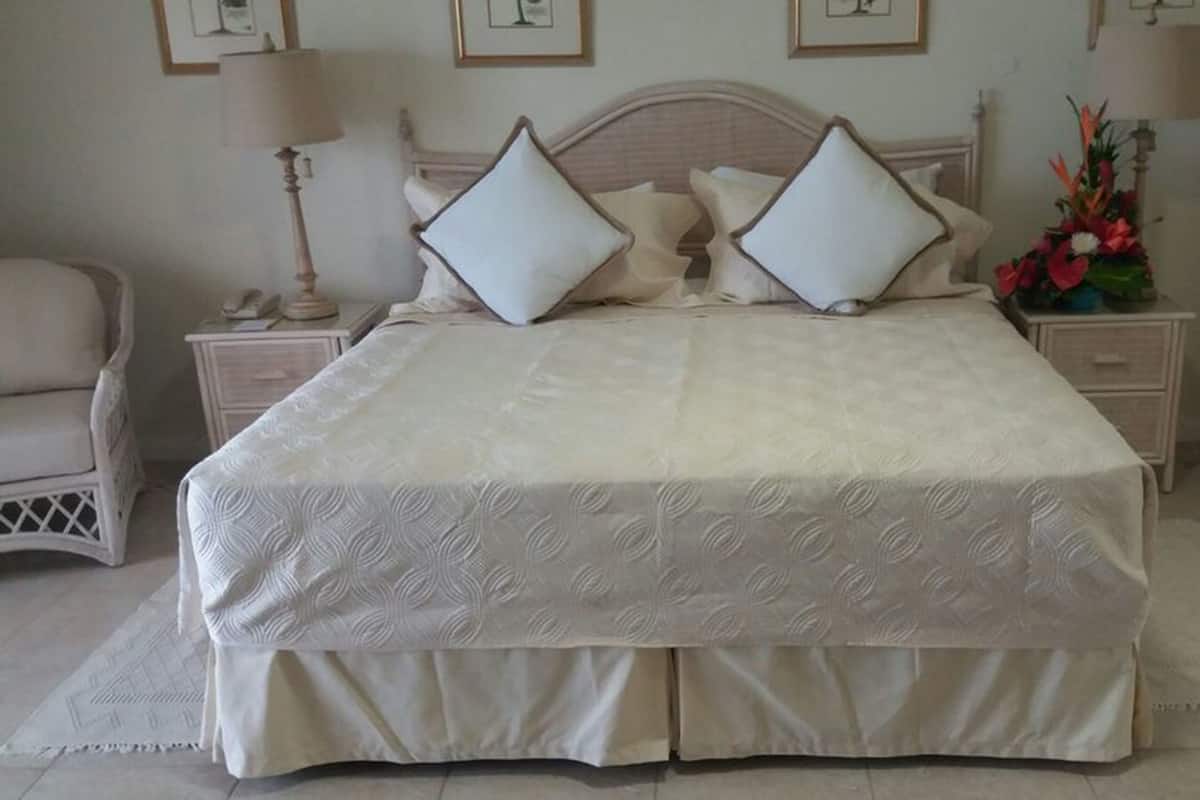 A neatly arranged bedroom with a large bed, two bedside tables, a chair, and a dresser.