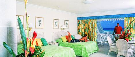 Habitación de hotel con dos camas, un comedor y vista al océano.