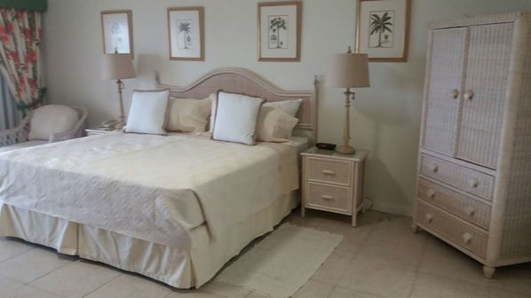 A bedroom with a large bed, bedside tables, a wardrobe, and framed pictures on the wall.