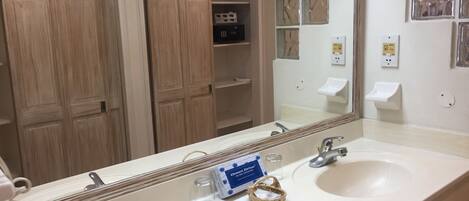 A bathroom with two sinks, a large mirror, and wooden cabinets.