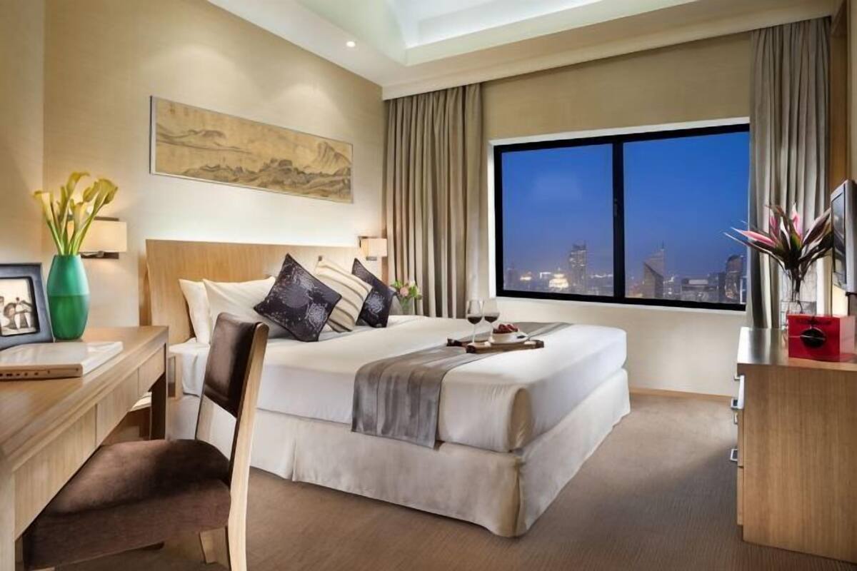 Une chambre d’hôtel avec un grand lit, un bureau, une chaise, une télévision et une vue sur la ville.
