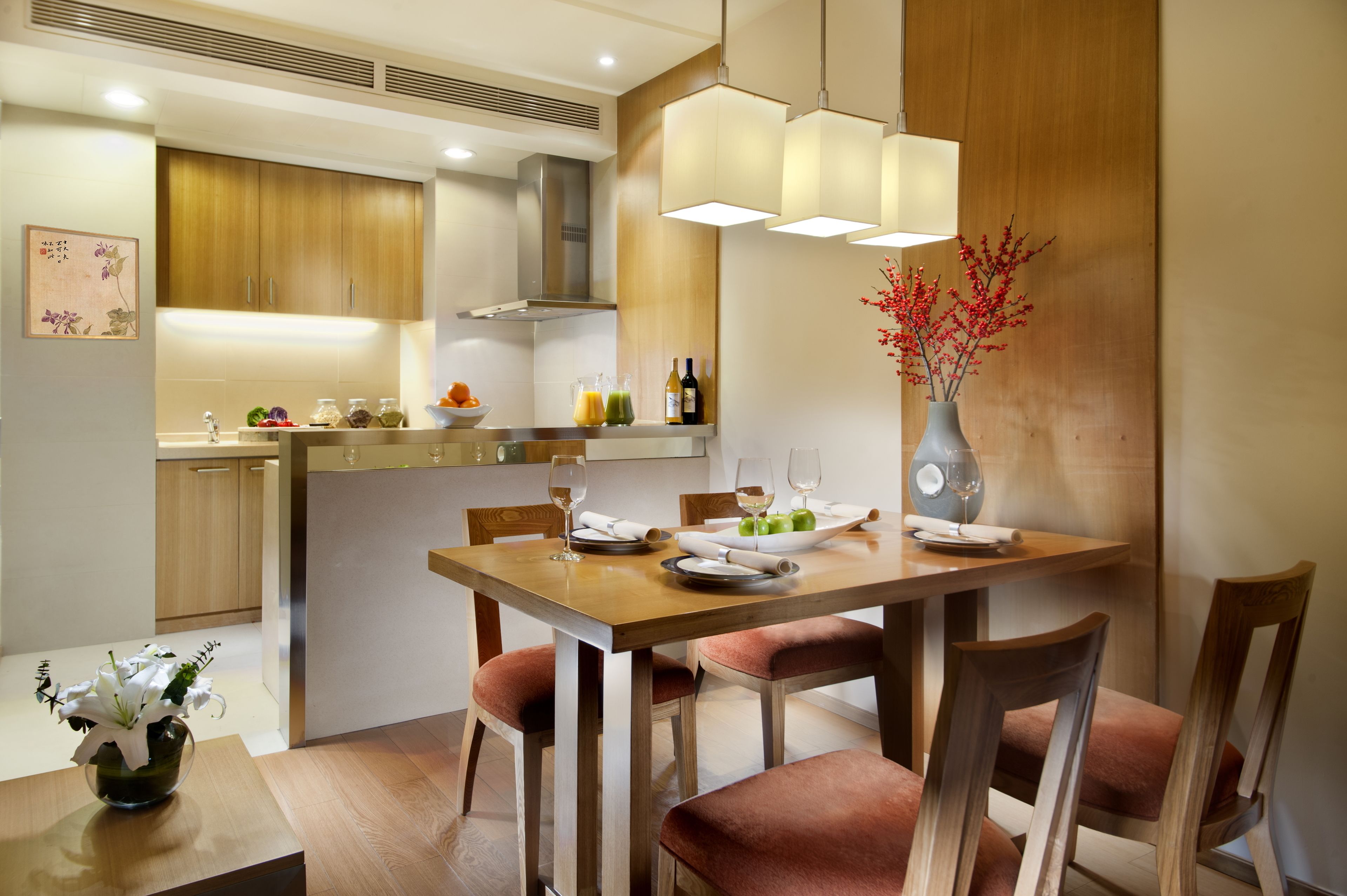 A modern kitchen with wooden cabinets, a dining table with chairs, and a vase with flowers.