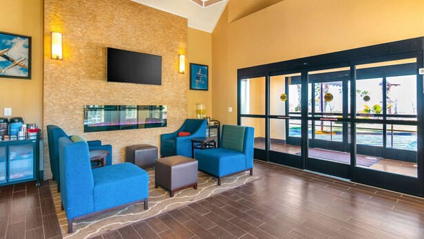 A lobby with blue seating, a flat-screen TV, and a glass wall offering a view of the pool. - Comfort Inn & Suites Mojave (Mojave)