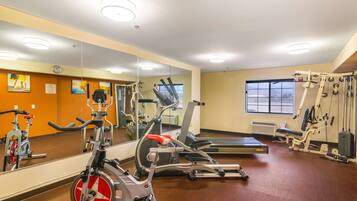 Un gimnasio con equipo de ejercicio, un espejo grande y una ventana.