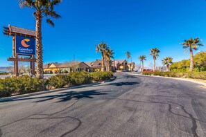 A Comfort Inn & Suites sign, a road, and palm trees. - Comfort Inn & Suites Mojave (Mojave)