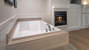 A modern bathroom with a freestanding bathtub, a fireplace, and a television mounted on the wall. - Cambria Landing Inn & Suites (Cambria)