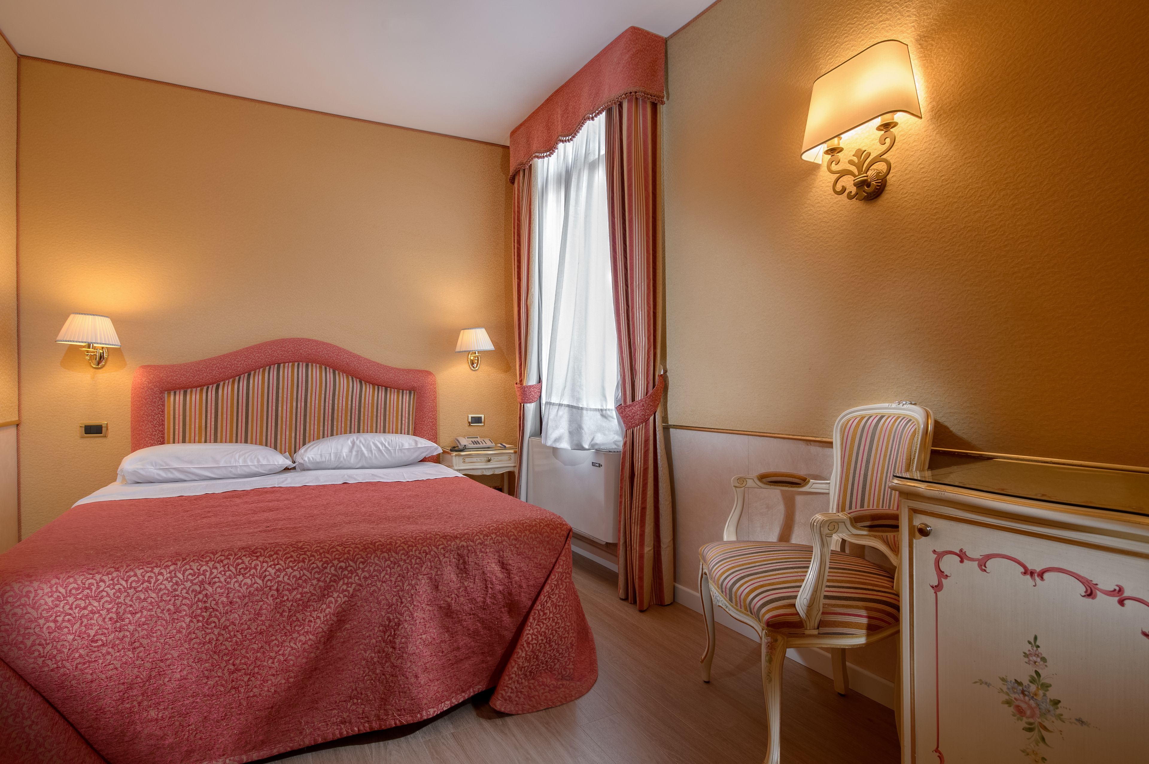 Une chambre d’hôtel avec un grand lit, deux lampes de chevet, une chaise et une commode.