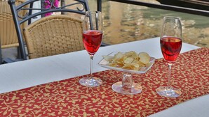 A table with two wine glasses and a bowl of chips, set against a backdrop of a canal with gondolas and buildings. - Alloggi Olimpia (Venice)