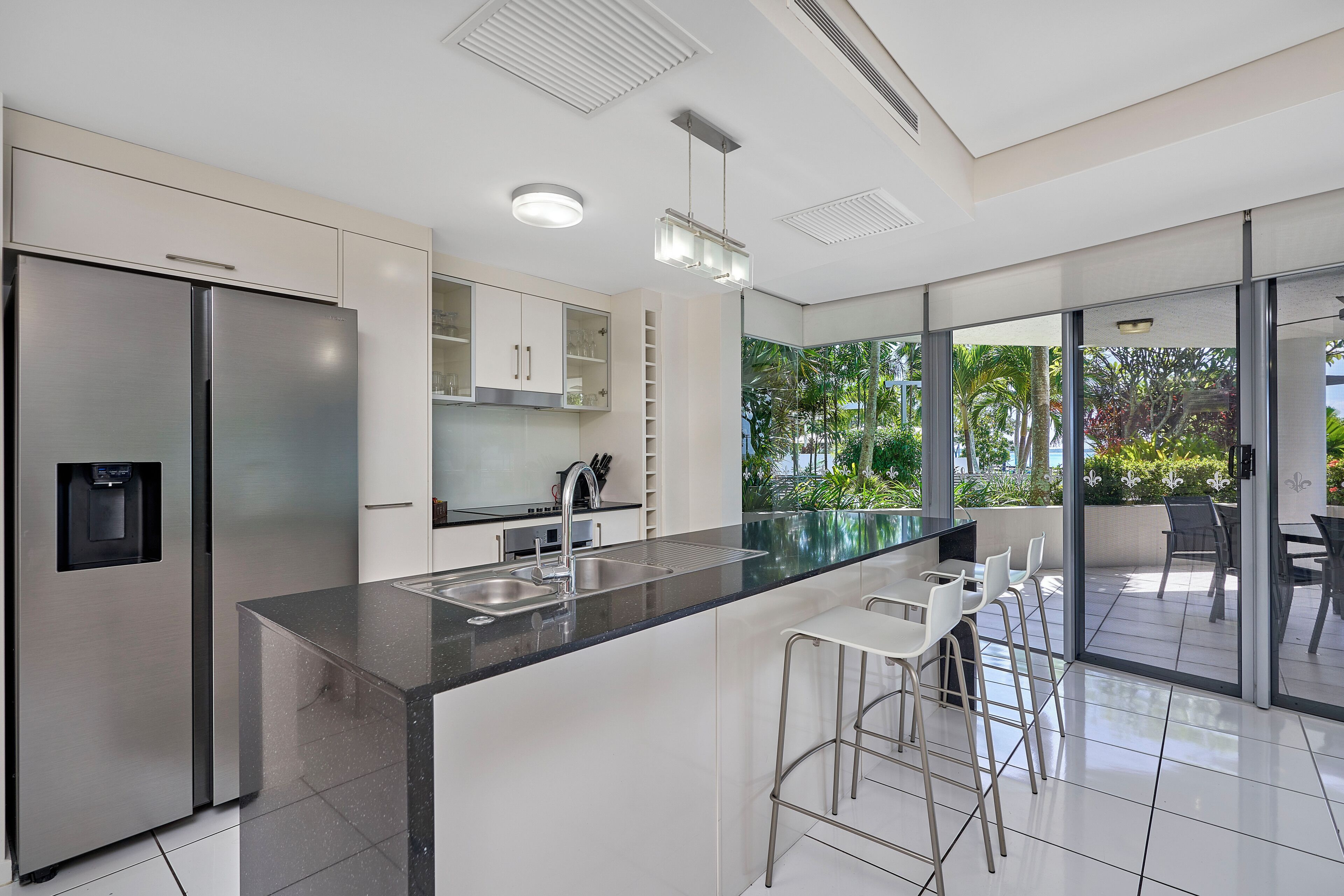 A modern kitchen with a large island, stainless steel appliances, and a view of the outdoors.