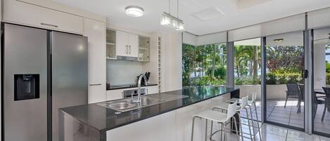 A modern kitchen with a large island, stainless steel appliances, and a view of the outdoors.