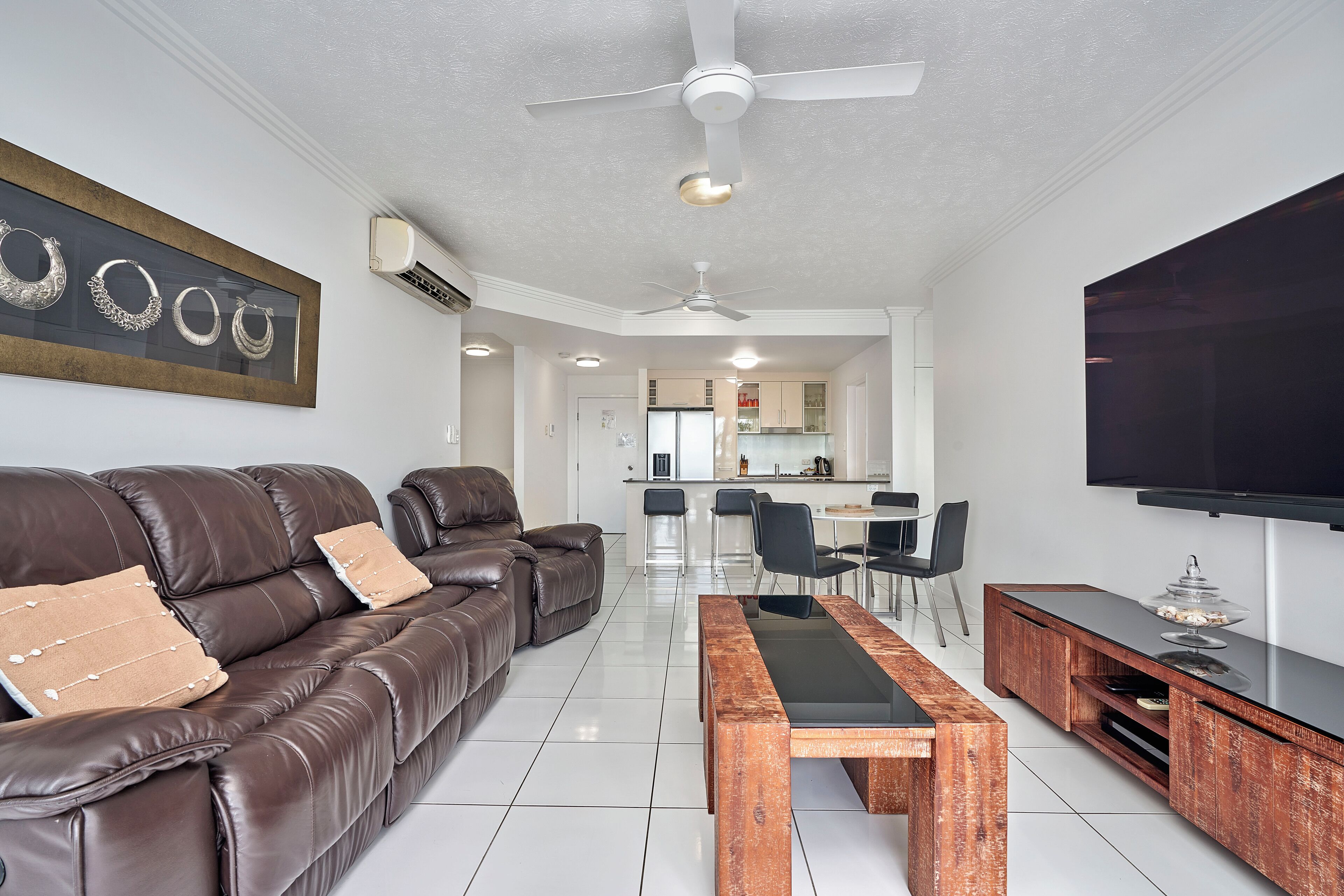 A modern living room with a leather sofa, a wooden coffee table, and a flat-screen TV.