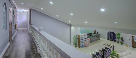 Un hall d’entrée spacieux avec un escalier central, un comptoir d’accueil et un espace détente.